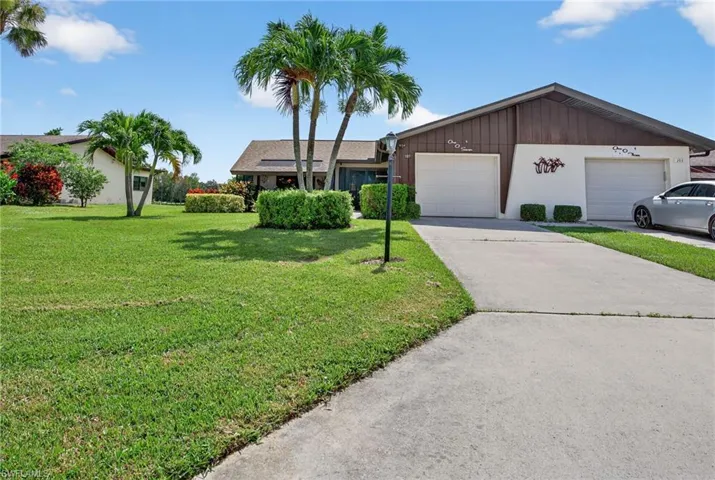 Ranch-style house featuring a garage, a front lawn, and driveway