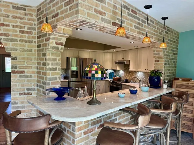 Kitchen featuring stainless steel appliances, a peninsula, decorative backsplash, and decorative light fixtures