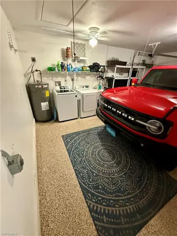 Garage featuring washer and dryer, electric water heater, and a ceiling fan