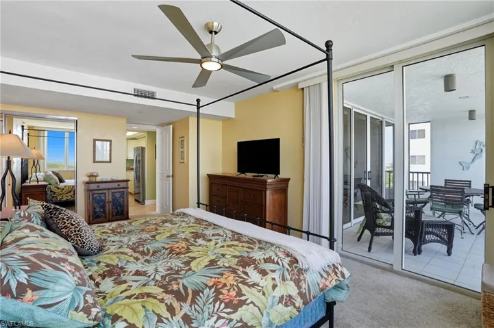 Bedroom with light colored carpet, ceiling fan, access to exterior, and freestanding refrigerator - Virtually Edited Image