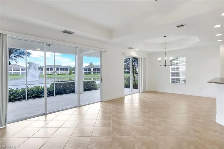 Unfurnished room featuring a tray ceiling, a notable chandelier, and light tile patterned flooring