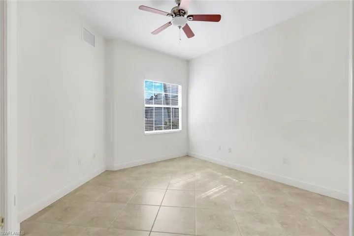 Tiled empty room featuring ceiling fan