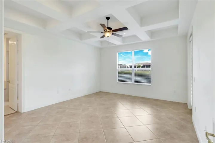 Tiled spare room featuring ceiling fan and coffered ceiling