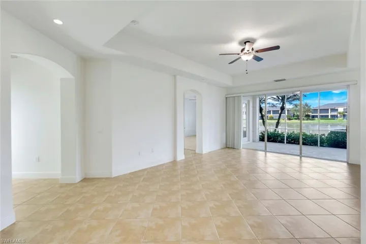 Tiled spare room featuring a raised ceiling and ceiling fan