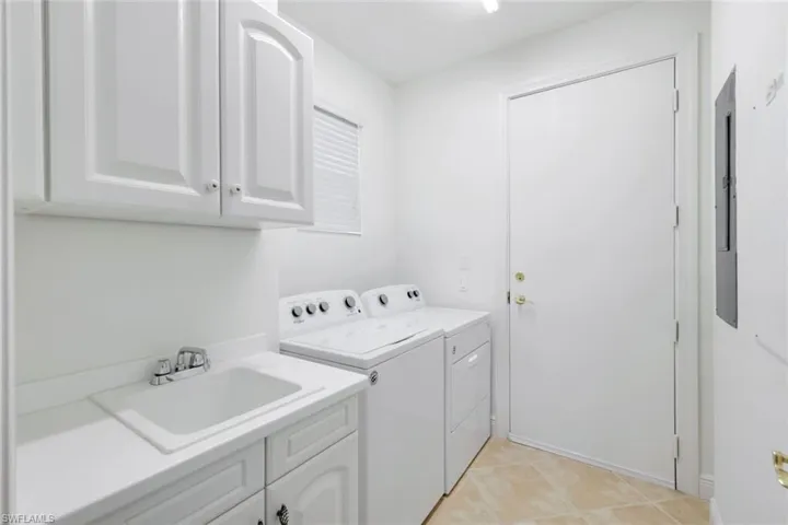 Laundry room with cabinets, sink, light tile patterned floors, and washer and dryer