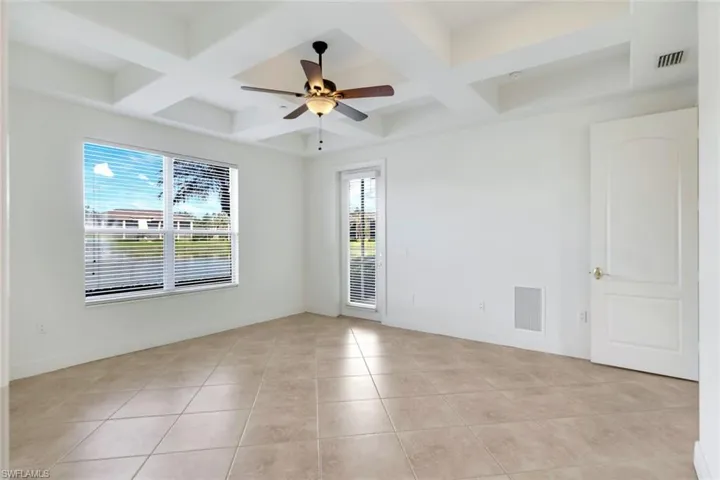 Spare room featuring ceiling fan, beamed ceiling, light tile patterned floors, and coffered ceiling