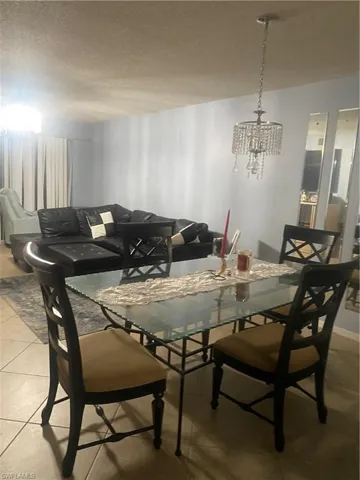 Dining room with a chandelier, tile patterned floors, and a textured ceiling