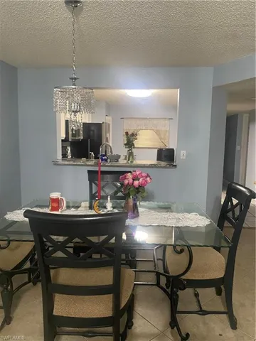 Tiled dining space featuring a textured ceiling and a chandelier