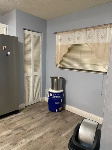 Detailed view of fridge, wood finished floors, and a textured ceiling