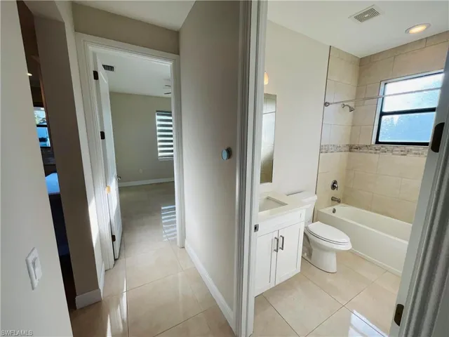 Bathroom with vanity, light tile patterned floors, tub / shower combination, and recessed lighting