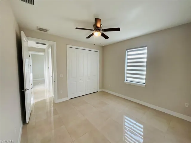 Unfurnished bedroom featuring a closet, light tile patterned floors, and ceiling fan