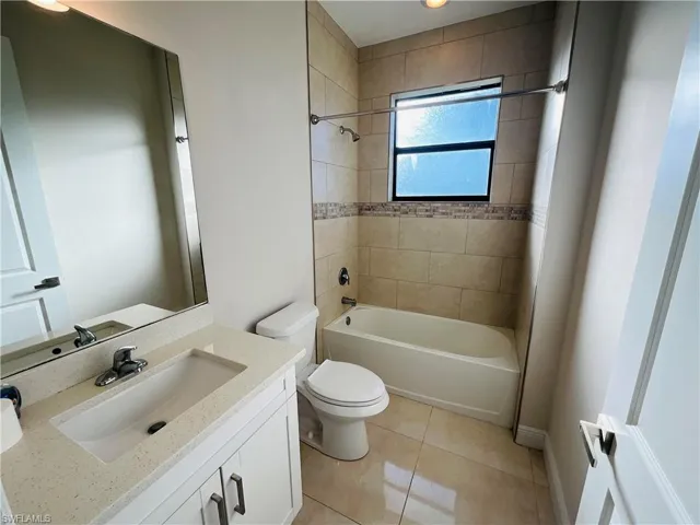 Full bath with vanity, shower / bath combination, and light tile patterned floors