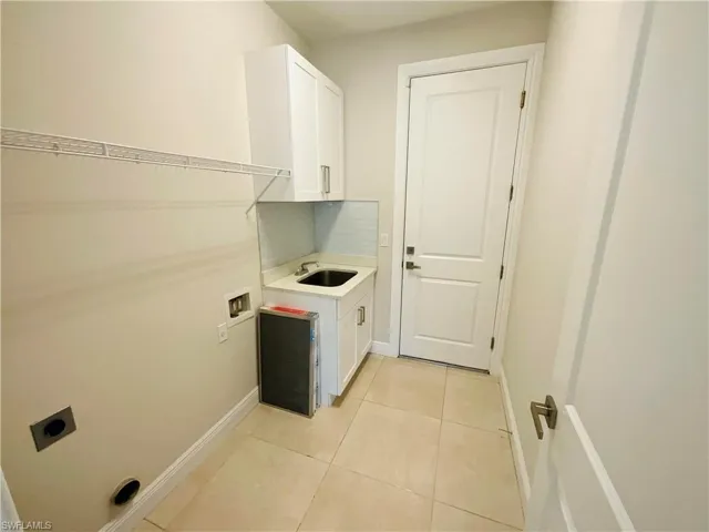 Washroom with light tile patterned floors, cabinet space, washer hookup, and hookup for an electric dryer