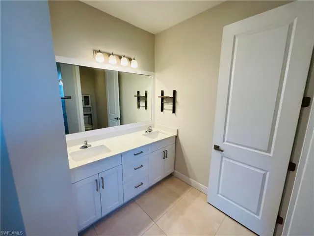 Full bath featuring double vanity and light tile patterned floors