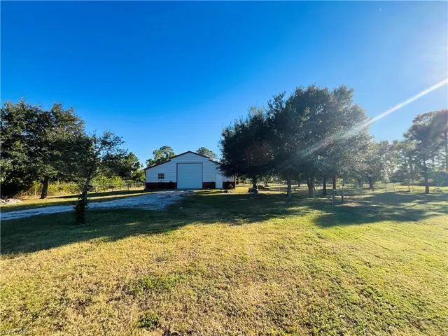 View of green lawn with an outdoor structure, an outbuilding, and a garage