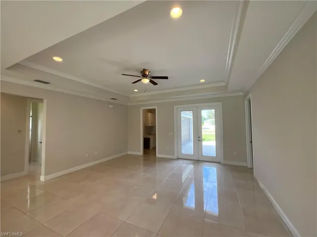 Unfurnished room with french doors, ornamental molding, a raised ceiling, recessed lighting, and light tile patterned floors