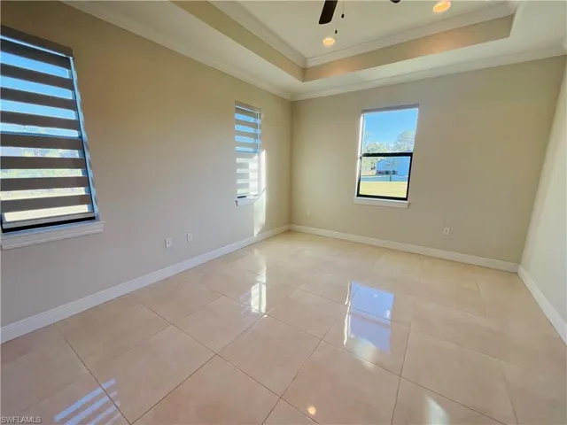 Unfurnished room with a tray ceiling, light tile patterned floors, ornamental molding, a ceiling fan, and recessed lighting