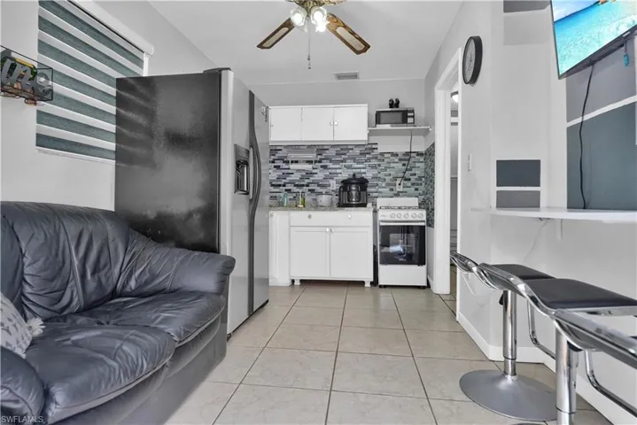 Kitchen with appliances with stainless steel finishes, decorative backsplash, ceiling fan, and white cabinets