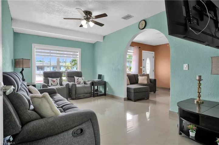 Living room featuring ceiling fan, a textured ceiling, plenty of natural light, and light tile patterned floors