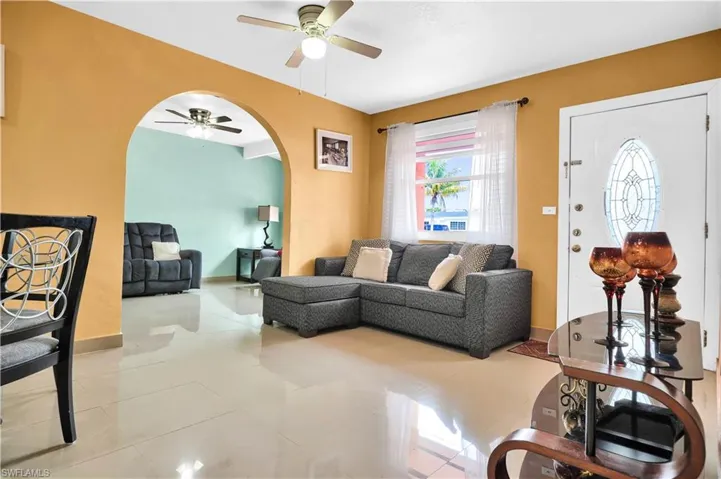 Living room with ceiling fan and light tile patterned flooring