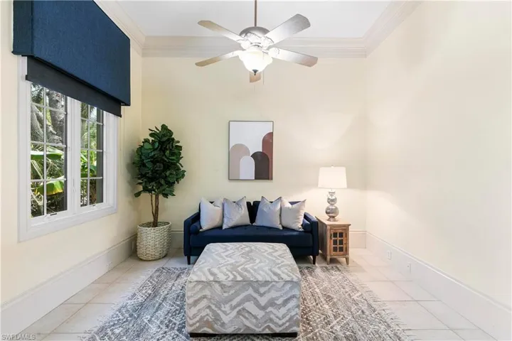 Living area with tile floors, ceiling fan, and crown molding