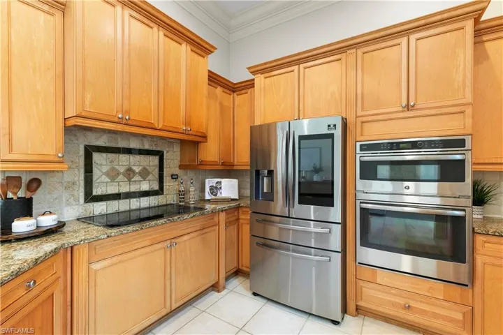 Kitchen with stainless steel appliances, light stone counters, and backsplash