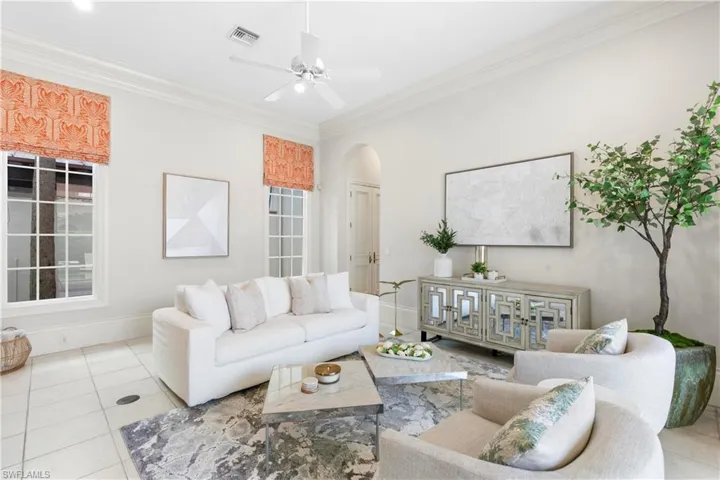 Living room featuring ornamental molding, ceiling fan, and light tile floors