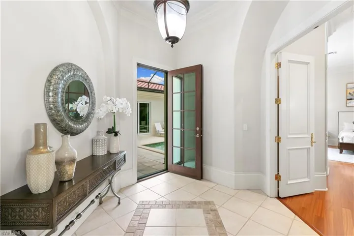 Tiled foyer entrance with crown molding and french doors