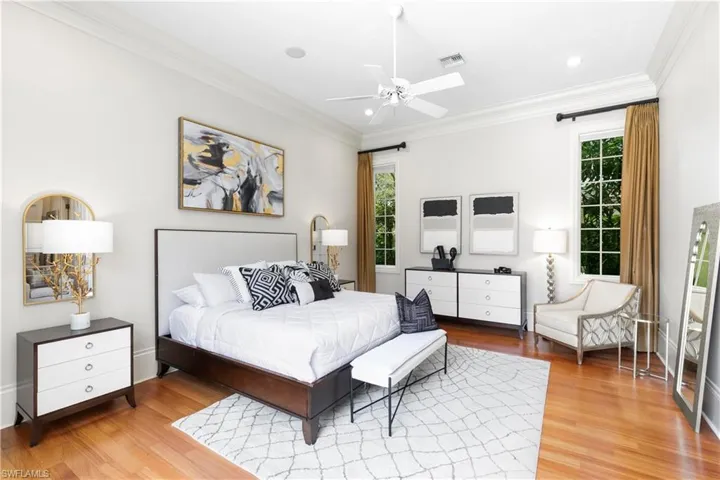 Bedroom featuring ceiling fan, multiple windows, light hardwood / wood-style flooring, and ornamental molding