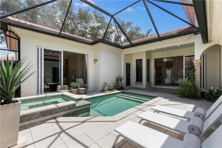 View of swimming pool with ceiling fan, glass enclosure, an in ground hot tub, and a patio