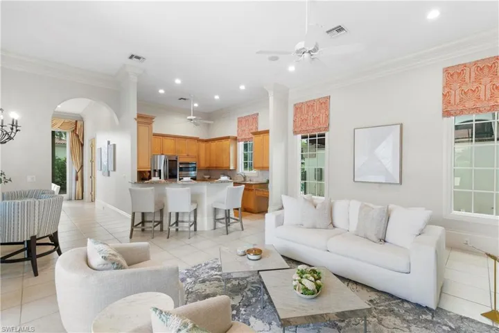 Living room featuring sink, ceiling fan, light tile floors, and crown molding