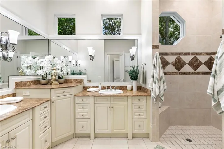 Bathroom with tile floors, a wealth of natural light, double sink, and vanity with extensive cabinet space