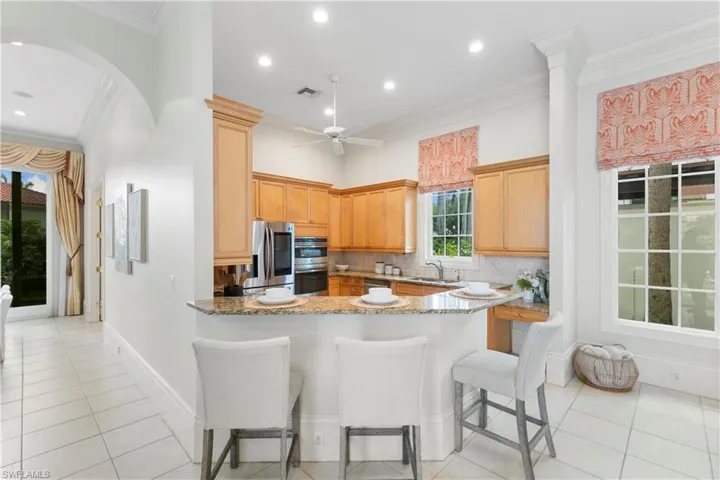 Kitchen with light stone countertops, sink, stainless steel appliances, and backsplash