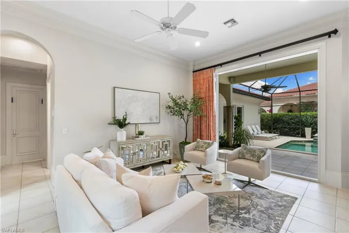 Living room featuring ceiling fan, light tile flooring, and ornamental molding
