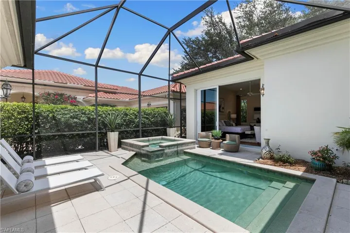 View of swimming pool with glass enclosure, an in ground hot tub, and a patio area