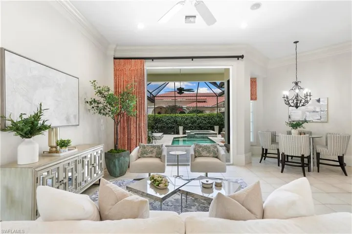 Tiled living room with ornamental molding and ceiling fan with notable chandelier