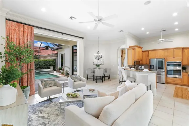 Tiled living room with ornamental molding and ceiling fan with notable chandelier