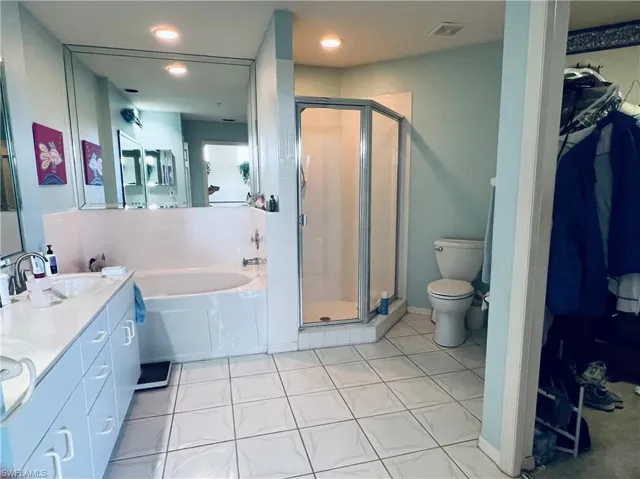 Full bathroom with tile flooring, separate shower and tub, and toilet