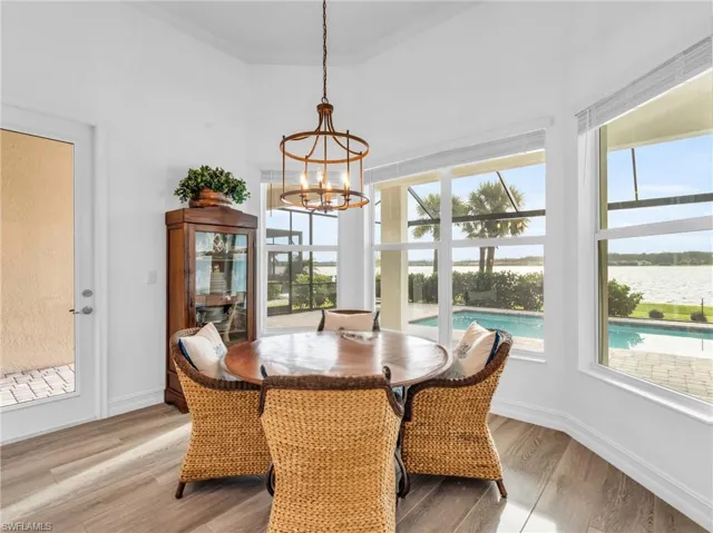 Dining space with an inviting chandelier, a wealth of natural light, a water view, and light wood-type flooringVirtually enhanced