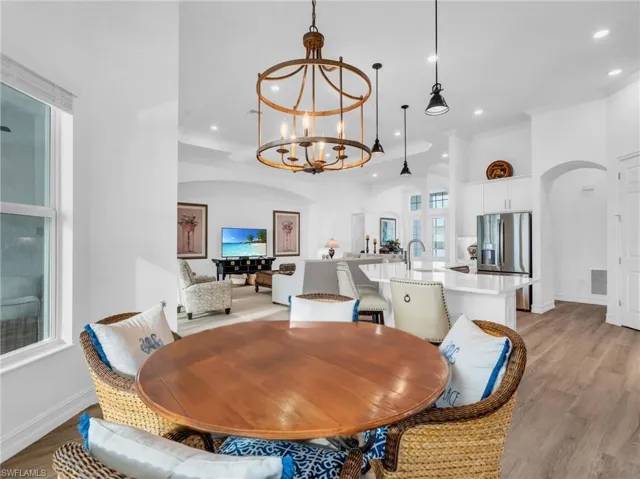 Dining area with ornamental molding, an inviting chandelier, and light hardwood / wood-style floorsVirtually enhanced