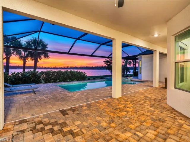 Pool at dusk featuring a lanai, a water view, and a patio areaVirtually enhanced