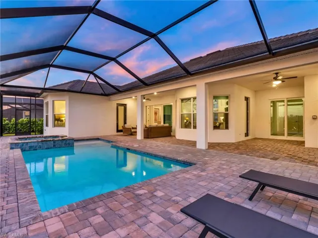 Pool at dusk featuring glass enclosure, ceiling fan, and a patioVirtually enhanced