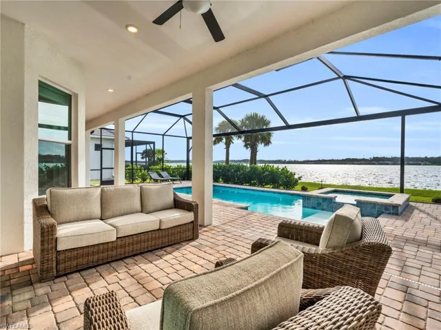 View of patio / terrace featuring a lanai, a pool with hot tub, an outdoor hangout area, a water view, and ceiling fanVirtually enhanced