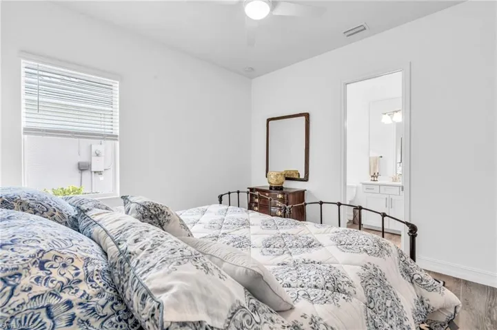 Bedroom with wood-type flooring, ceiling fan, and ensuite bathroomVirtually enhanced