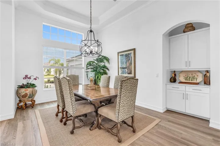 Dining space featuring light wood-type flooring, crown molding, a tray ceiling, and a chandelierVirtually enhanced