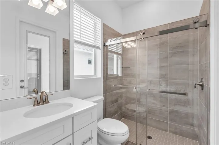 Bathroom featuring vanity, toilet, a shower with door, and a wealth of natural lightVirtually enhanced