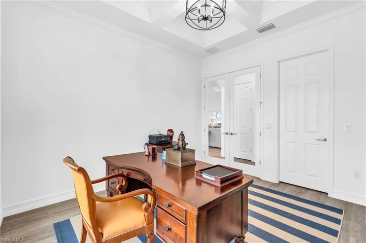 Office space with coffered ceiling, beamed ceiling, hardwood / wood-style flooring, ornamental molding, and a chandelierVirtually enhanced