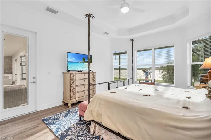 Bedroom with ornamental molding, wood-type flooring, ceiling fan, and a raised ceilingVirtually enhanced