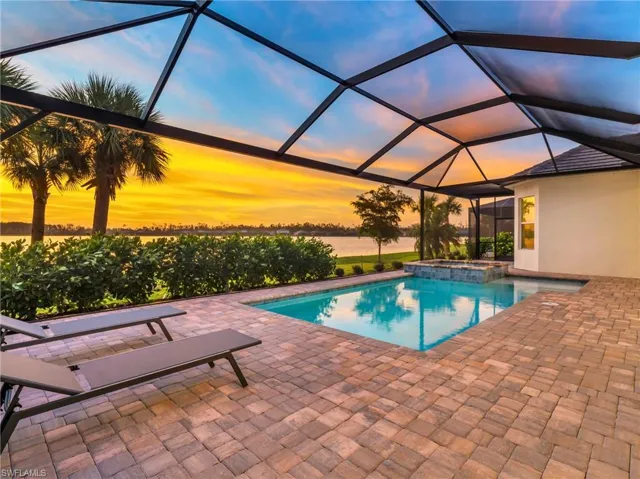 Pool at dusk with a lanai, a water view, an in ground hot tub, and a patio areaVirtually enhanced