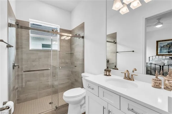 Bathroom with walk in shower, vanity, toilet, and ceiling fanVirtually enhanced